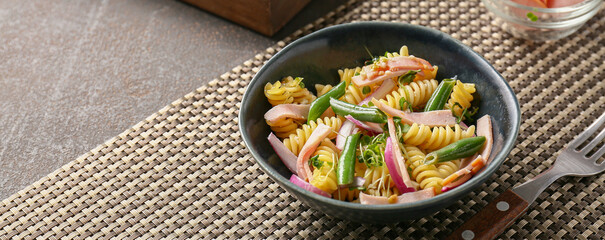 Bowl with tasty pasta salad on table