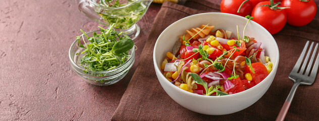 Bowl with tasty pasta salad on brown background