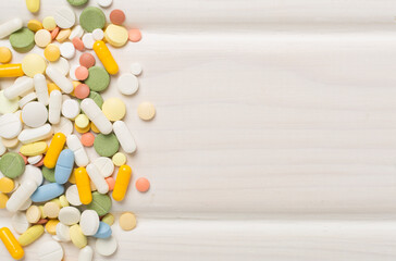 Different medical pills and capsules on wooden background, top view