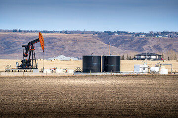Pump jack working on a rural property for the oil and gas industry at Springbank Rocky View County Alberta Canada.