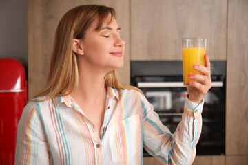 Young woman with glass of orange juice in kitchen, closeup