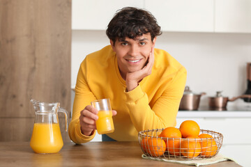 Fototapeta na wymiar Young man with juice and oranges in kitchen
