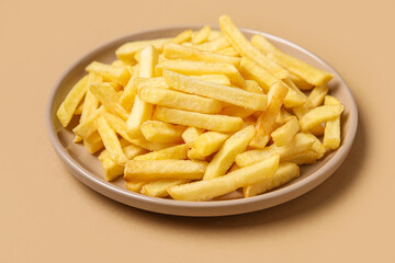 Plate with golden french fries on beige background, closeup