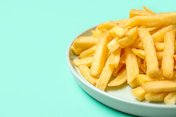 Plate with golden french fries on turquoise background, closeup