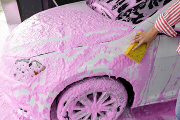 Woman cleaning the car with a violet foam