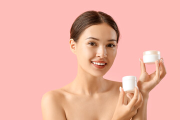 Obraz na płótnie Canvas Beautiful Asian woman with jars of cream on pink background, closeup
