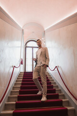 A well-dressed man stands confidently on the stairs of a Venetian building in Italy. The architectural style is likely Venetian, adding to the luxury collection of Venice images.