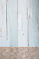 Blue and white rustic wooden background with burlap ribbon going across the bottom of the table. Overhead top view.