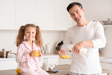 Cute little girl with her dad making breakfast in kitchen