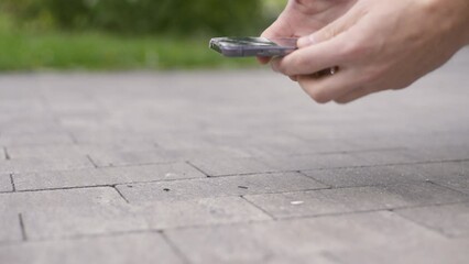 An unrecognizable man drops his smartphone on the pavement and picks it up holding a broken smartphone in his hand, Super slow-motion footage 4K UHD B-Roll