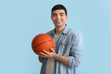 Happy young man with ball on blue background