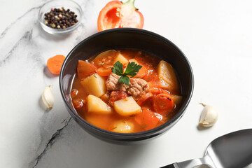 Bowl with delicious beef stew and different ingredients on white background