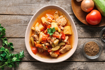Bowl with delicious beef stew and parsley on wooden background