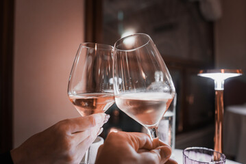A couple toasting with white wine glasses at a cozy restaurant in Venice, Italy. The warm and inviting setting captures a beautiful moment in the romantic city.