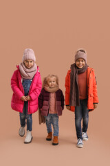 Cute children in winter clothes on beige background