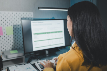 Young Asian businesswoman working overtime in a dark office, Young woman working on the laptop late at night, working overtime in the office to finish the project within the deadline.