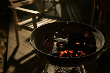 A glowing camp fire providing comfortable lights and barbecue grill pit with glowing and flaming of fire with hot charcoal briquettes with night time outdoor background