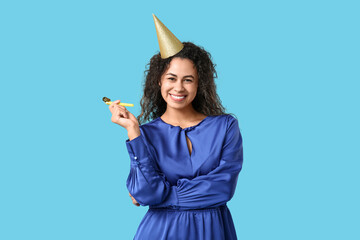 Young African-American woman celebrating birthday on blue background