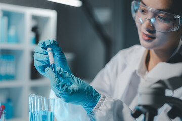 Young scientists in sterile clothing and safety goggles sitting at table conducting research...