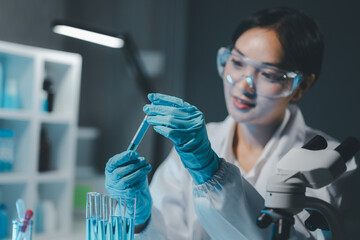 Young scientists in sterile clothing and safety goggles sitting at table conducting research...