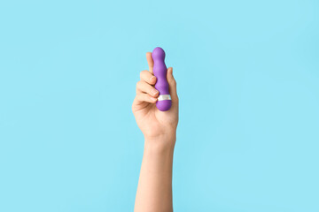 Female hand with vibrator on color background, closeup