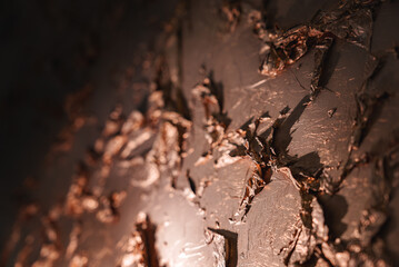 Close-up of a smooth, shiny piece of chocolate with a dark background and a light source behind it....