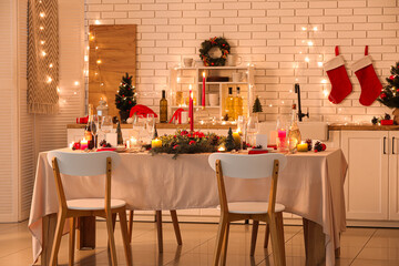 Festive table setting with Christmas decorations and glowing lights in kitchen at evening