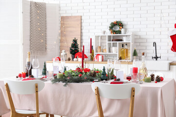 Festive table setting with Christmas decorations and burning candles in kitchen