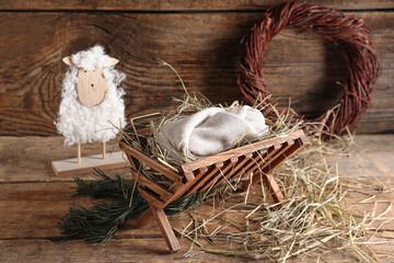 Manger with dummy of baby and sheep on wooden background. Concept of Christmas story