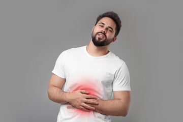 Man suffering from stomach pain on grey background