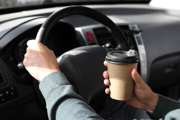 Coffee to go. Man with paper cup of drink driving his car, closeup