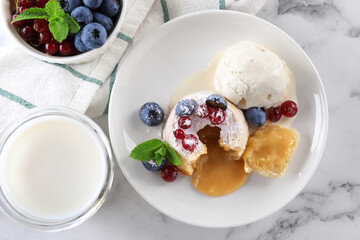 Tasty vanilla fondant with white chocolate, berries and ice cream served on white marble table,...