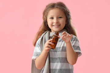 Sick little girl with cough syrup on pink background