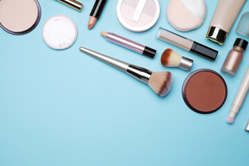 Face powders and other decorative cosmetic products on light blue background, flat lay. Space for text