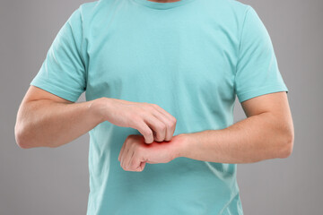 Allergy symptom. Man scratching his hand on light grey background, closeup