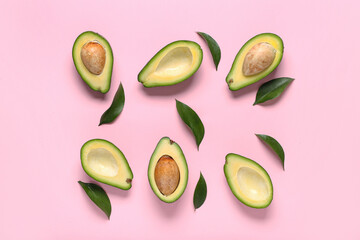 Halves of fresh ripe avocados and leaves on pink background