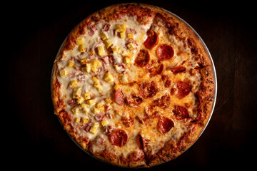 Pizza topped half with pepperoni and half with pineapple and ham