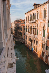 Fototapeta na wymiar Explore the serene and picturesque canals of Venice, Italy with this calming view of a canal. The tranquil brown and green hues create a peaceful atmosphere.
