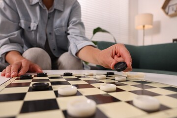 Woman playing checkers at home, closeup view