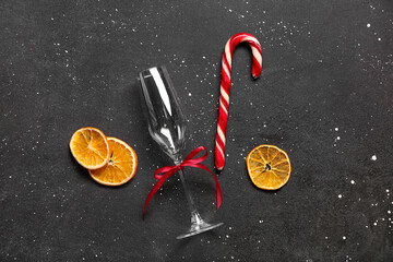 Dried orange slices with Christmas candy cane and glass on black background