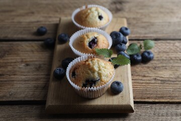 Delicious sweet muffins with blueberries and mint on wooden table, closeup