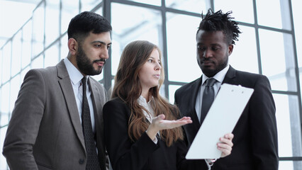 Portrait of three people in business wear discussing document in office.