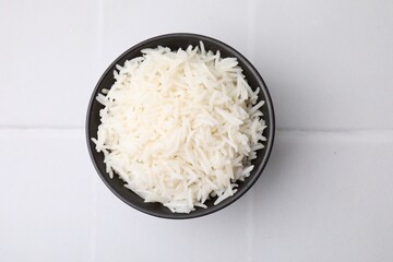 Bowl of delicious rice on white table, top view