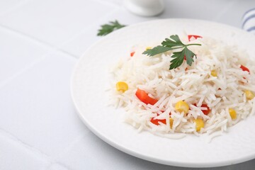 Delicious rice with vegetables and parsley on white table, closeup