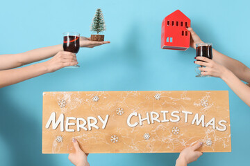 Female hands with glasses of warm mulled wine and Christmas decor on blue background