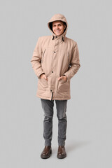 Young man in stylish puffer jacket on grey background