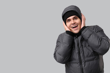 Young man in stylish puffer jacket on grey background