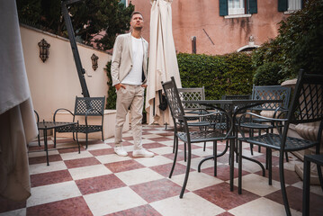 Urban businessman standing on checkered floor in front of modern city building in Venice, Italy.