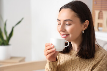Pretty young woman drinking fresh coffee in living room, closeup