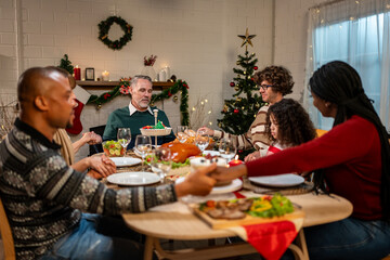 Multi-ethnic big family saying a prayer before having Christmas dinner. 